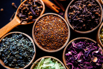 Various dried tea leaves in wooden bowl. Dried herbs tea leaves close up. Different dry herbs and flowers for making healthy tea background.
