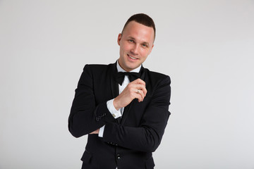 Stylish fashion portraits of a charismatic handsome man in a black tuxedo suit with a bow tie. Emotions, black and white photo, dramatic, close-up. Isolated, white background.