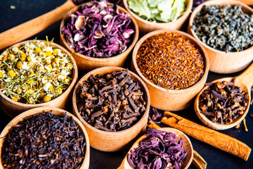 Various dried tea leaves in wooden bowl. Dried herbs tea leaves close up. Different dry herbs and flowers for making healthy tea background.