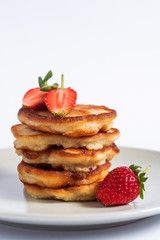 Russian traditional pancakes oladi with fresh strawberries. Vertical. Close up.