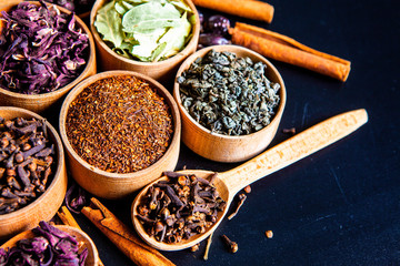 Various dried tea leaves in wooden bowl. Dried herbs tea leaves close up. Different dry herbs and flowers for making healthy tea background.