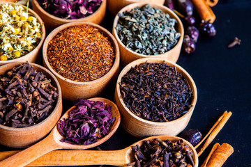 Various dried tea leaves in wooden bowl. Dried herbs tea leaves close up. Different dry herbs and flowers for making healthy tea background.