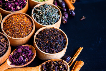 Various dried tea leaves in wooden bowl. Dried herbs tea leaves close up. Different dry herbs and flowers for making healthy tea background.