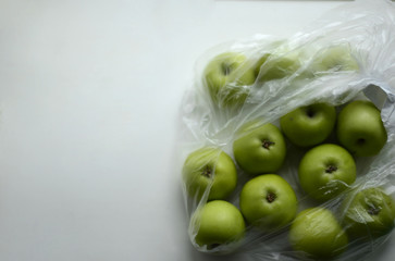 Green little apples in a plastic bag on a white background. Free space for text.