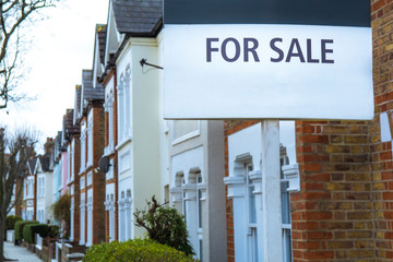 Obraz premium 'For Sale' estate agent sign on street of terraced houses
