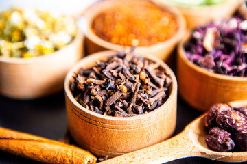Various dried tea leaves in wooden bowl. Dried herbs tea leaves close up. Different dry herbs and flowers for making healthy tea background.