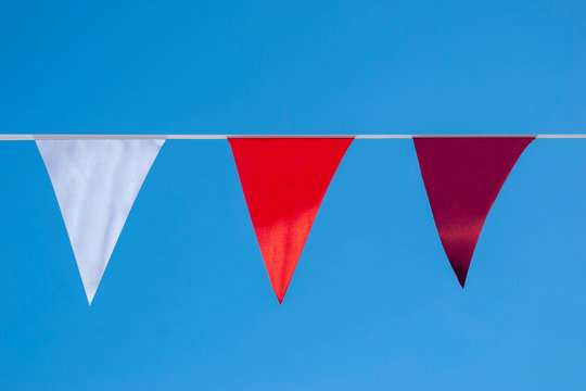 Three triangular flags of different colors against a blue sky
