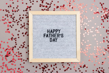 Letterboard with quote Happy fathers day on gray background. Holiday concept with red stars confetti.