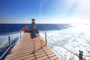 wooden bridge to the blue ocean ,sun is shining brightly in blue sky