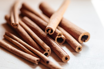 Die braune, gerollte Rinde des Zimtbaumes liegt zu Zimtstangen geschnitten auf einer hellen Holzunterlage.