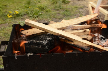 
Relax in the fresh air. On a green lawn there is a barbecue, a fire burns, charred firewood.
