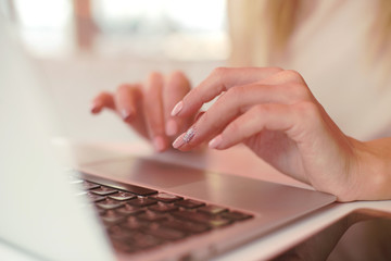 female hands are printing on a laptop in a cafe 