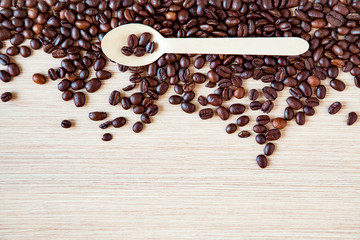 coffee beans on a wooden table, with an eco-friendly wooden spoon .Light wooden background, with space for text and copying