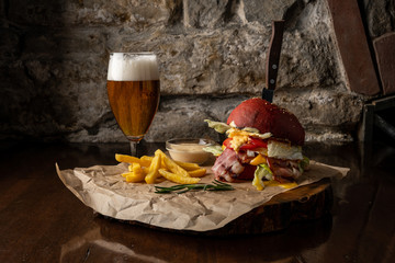 Big tasty burger and fries with beer on background on the wooden table
