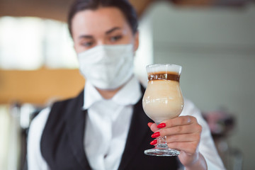 work of a waiter in a restaurant in a medical mask.