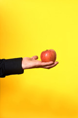hand holding a apple on yellow background