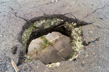 Ein Loch in einem Betonboden. Duch das Loch in der Erde kann man die untere Ebene der Strasse sehen.  - obrazy, fototapety, plakaty