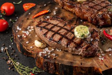 two large pieces of bone steak on wooden board next to sauce waiting for served ready.