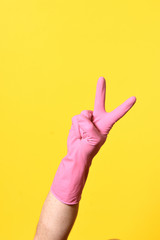 hand with glove and v sign on yellow background