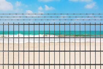 Quarantine due to Novel Coronavirus COVID-19 2019 n-CoV Concept. Metal Fence with Barbed Wire in front of Sand Ocean Beach. 3d Rendering