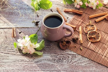 Cup of coffee, spices, apple flowers on a wooden windowsill, home comfort concept