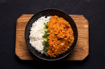 Dhal Indian cream lentil soup on a wooden plank on a black background.