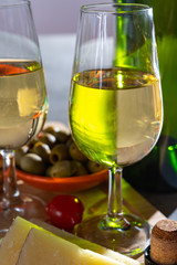 Glasses of dry fino sherry wine served with spanish tapas, manchego cheese, green olives, cheese crackers