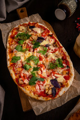 High Angle View of Fresh Baked Margherita Pizza Topped with Tomatoes, Cheese and Fresh Basil on Wooden Paddle