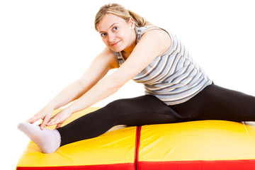 Plakat fitness girl wearing black chausses doing stretching on a mat