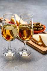 Glasses of dry fino sherry wine served with spanish tapas, manchego cheese, green olives, cheese crackers