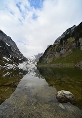 reflecting mountain lake in the swiss alps with snow images in the background