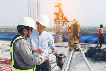 Management consulting with engineers working at construction site and holding blueprint in his hand for management business plan.