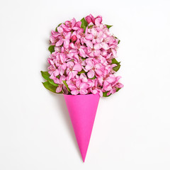 Blossom spring bouquet in ice cream cone. Pink bloom flowering, top view. Minimal creative concept. Springtime blooming background. Trendy pink vivid fashionable design.