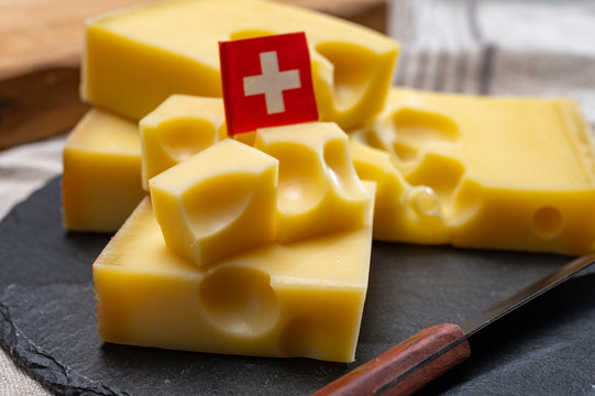 Block of Swiss medium-hard yellow cheese emmental or emmentaler with round holes and cheese knife