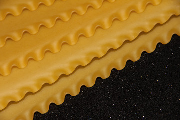 Pasta on a black shiny background. Lasagna sheets on a dark background. Food frame.