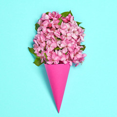 Blossom spring bouquet in ice cream cone. Pink bloom flowering, top view. Minimal creative concept. Springtime blooming background. Trendy blue vivid fashionable design.