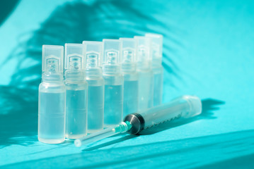 Bautiful medicine ampulla syringe needle on the blue background macro photo with sun light and shadows. Health care