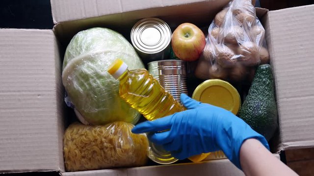 Volunteer puts food in a donation box, closeup. Charity and donations. Help during Covid-19 quarantine. Food delivery