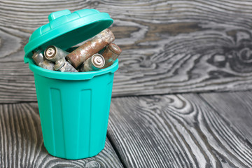 Trash can with lid filled with waste batteries. The batteries are covered with corrosion. Close-up...