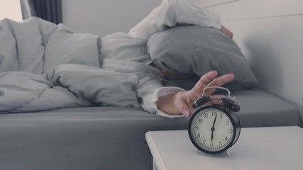 Close up Clock on the bed Asian woman wake up and disturbed by alarm clock early morning - Powered by Adobe