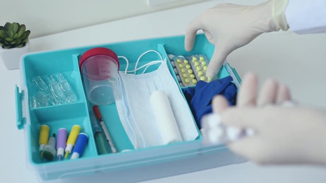 Woman in gloves take lancet for blood and test cup from first aid kit. Home medicine box with a medical items. Healthcare and medicine concept.