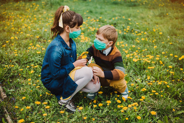 Fototapeta premium Children in medical masks cut dandelions in the garden. The concept of protection against coronovirus and social distance