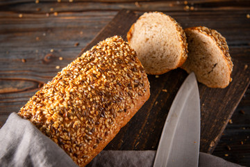 grain bread, slices, knife on a gray towel on a dark background close-up, food, top view