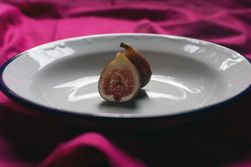 single fig on old plate, still life style, purple background, front view