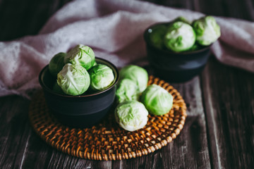 Choux de Bruxelles dans un petit bol céramique posé sur la table en bois en cuisine