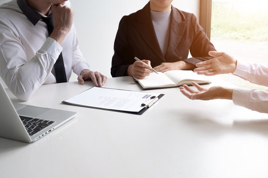 The manager is interviewing about work with two applicants in the office room.