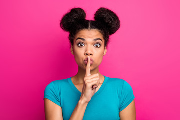 Fototapeta na wymiar Shh. It's examination time. Closeup photo of beautiful crazy dark skin lady two buns hairdo hold finger on lips wear blue casual t-shirt isolated bright pink color background
