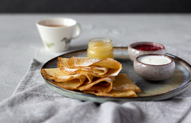 Folded thin crepes served with raspberry jam, sour cream and honey. Tasty breakfast concept