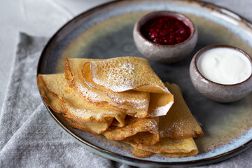 Folded thin crepes sprinkled with sugar powder and served with rasberry jam and sour cream. Tasty dessert