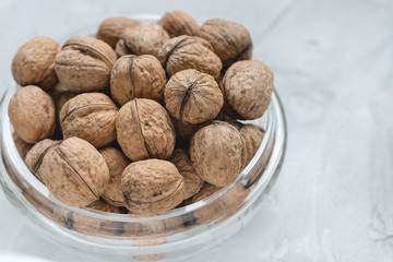 Uncracked walnuts in shell in bowl on gray background, concept of healthy eating vegan food. Close up, selective focus, copy space.